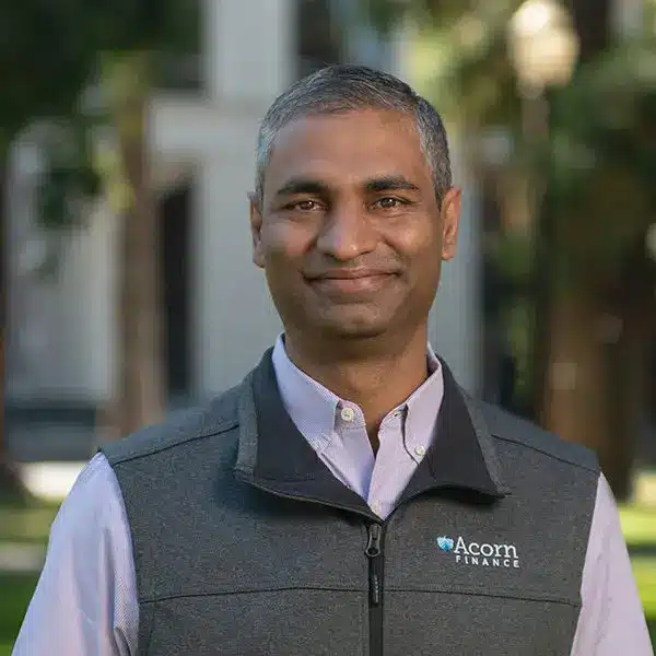 Smiling man outdoors in vest with acorn finance logo.
Smiling man outdoors in vest with acorn finance logo.
