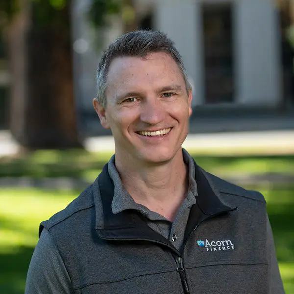 Man outdoors in jacket with "acorn finance" logo, smiling.
Man outdoors in jacket with "acorn finance" logo, smiling.