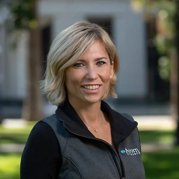 Smiling woman outside in black jacket with company logo.
Smiling woman outside in black jacket with company logo.